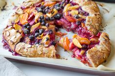 a close up of a pie on a pan with berries and almonds in it