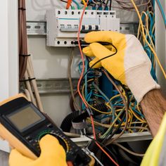 an electrician is checking the wires in his home electrical box with a multimeter