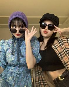 two young women wearing sunglasses and hats posing for the camera with their hands on their hipss