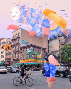 a woman riding a bike down a street under a kite shaped like a bird flying over her head