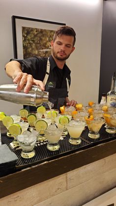 the bartender is making cocktails at the bar with lemons and lime wedges