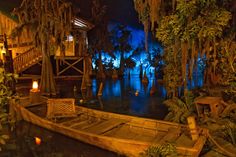 a boat sitting on top of a river surrounded by trees and plants at night time