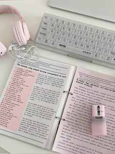 an open book sitting on top of a desk next to a keyboard and headphones