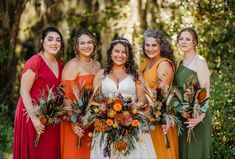 a group of women standing next to each other holding bouquets in their hands and smiling at the camera