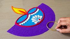 someone is holding a pair of scissors near a purple hat with flowers and pearls on it