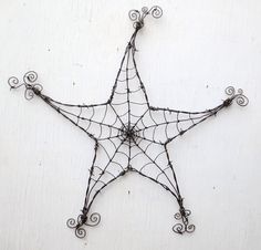 a wire star hanging on the side of a wall with an iron decoration attached to it