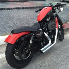 a red and black motorcycle parked on the side of the road next to a curb