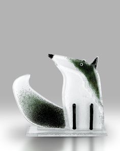 a glass figurine of a fox on a white base with black legs and tail