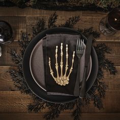 a plate with a fork, knife and skeleton hand on it next to some wine glasses