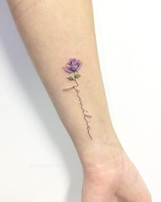 a small purple rose tattoo on the left inner forearm and wrist with words written in cursive writing