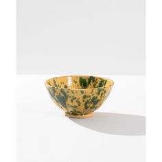 a yellow and green bowl sitting on top of a white table