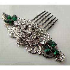 a close up of a hair comb with green and white jewels on it's side