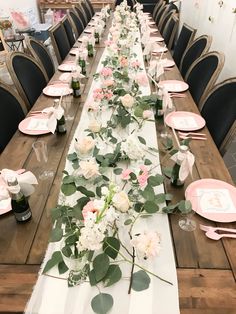 the long table is set with pink and white flowers, greenery, and place settings