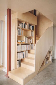 there is a book shelf with many books on it and stairs leading up to the second floor