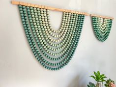 two green beads are hanging on the wall next to a potted plant and vase