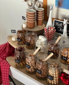 an assortment of cookies and hot chocolates in glass jars on a table with wooden spoons