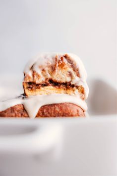 a cinnamon roll with icing on it sitting in a white bowl