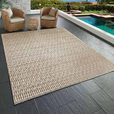 an outdoor area rug with two chairs and a pool in the background