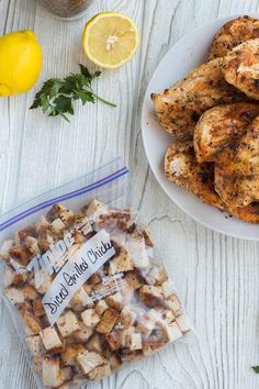 chicken wings and lemons on a white table next to a bag of seasoning