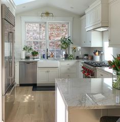 a kitchen with white cabinets and marble counter tops, along with an island in the middle