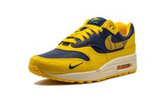 The Women’s Nike Air Max 1 Co. Jp “Michigan Snakeskin” is a women’s-exclusive colorway of the retro running shoe included in Nike’s bringback of the “Concept Japan” collection.  The bold “Michigan Snakeskin” colorway features a Midnight Navy leather base with Varsity Maize textured pebbled leather overlays.  Yellow reptilian-designed Swooshes appear on the side.  Classic “Nike Air Max 1” branding is printed on the tongue and a small navy Swoosh is embroidered on the forefoot.  Additional “Nike A Retro Running Shoes, Nike Air Max 1, Air Max Women, Stadium Goods, June 21, Navy Leather, Midnight Navy, Air Max 1, Running Shoe