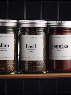 three jars filled with spices sitting on top of a wooden shelf