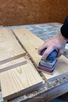 a person using a sanding machine on wood planks to finish a piece of furniture