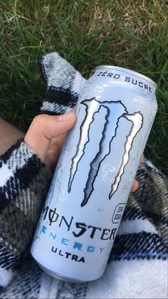 a person holding up a can of monster energy