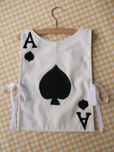 a white bag with playing cards on it hanging from a wooden hanger over a checkered table cloth