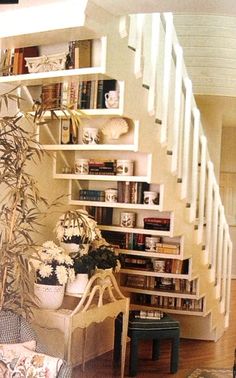 a living room filled with lots of furniture and bookshelves next to a stair case