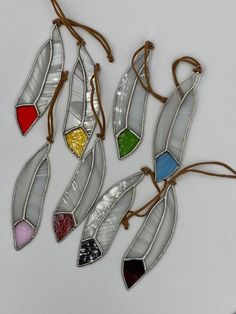 four pieces of stained glass hanging on a string with colored stones in the shape of leaves