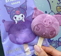 a hand holding a purple animal lollipop