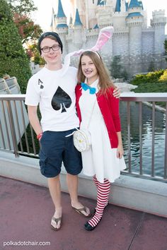 a man and woman standing next to each other in front of a castle at disneyland