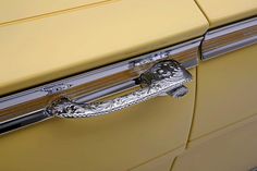 the door handle on an old yellow car is ornately decorated with silver details and designs