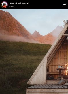 a person sitting in front of a fire pit on top of a wooden platform with mountains in the background