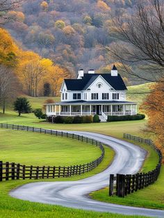 a large white house sitting on the side of a lush green field next to a road