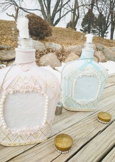 two decorative bottles sitting on top of a wooden table next to some rocks and trees