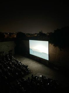 an outdoor movie screen with people watching it at night