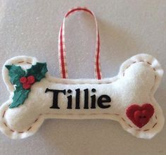 a white dog bone ornament with holly leaves and a red heart on it