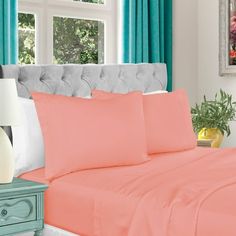 the bed is made with coral colored sheets and pillows