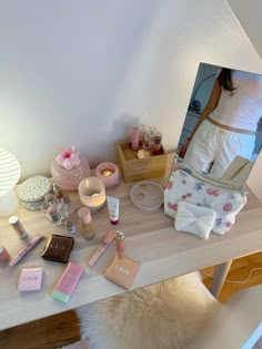 a woman is standing in front of a mirror with makeup and other items on the table