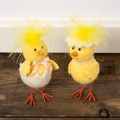 two stuffed chickens are sitting next to each other on a wooden surface, one is yellow and the other is white