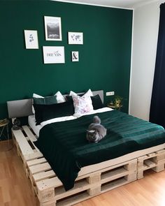 a cat laying on top of a bed made out of wooden pallets in a bedroom