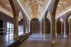 the inside of an empty building with columns and brickwork on the walls, along with wooden flooring