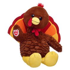 a stuffed turkey sitting on top of a white floor next to a red and orange pillow