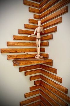 a wooden doll standing on top of a shelf made out of wood planks in the shape of a human figure