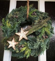 a wreath hanging on the front door decorated with pine cones, evergreen and star ornaments