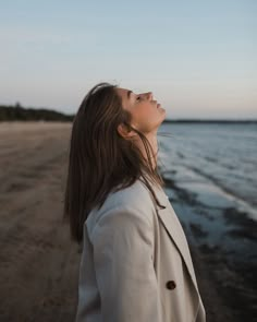 a woman standing on the beach looking up into the sky with her eyes wide open