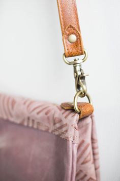 a close up of a purse with a metal hook on the handle and leather strap