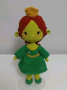 a crocheted doll with a red hair wearing a green dress and a gold crown